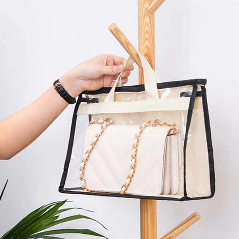 Hand hanging a clear handbag storage cover with black trim on a wooden peg.