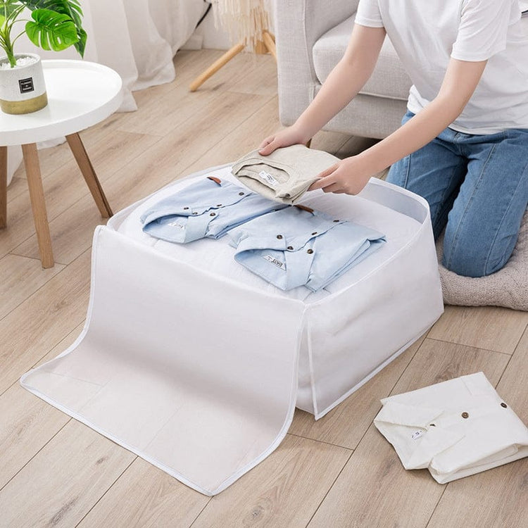 Clothes being placed inside an open white fabric storage cube.