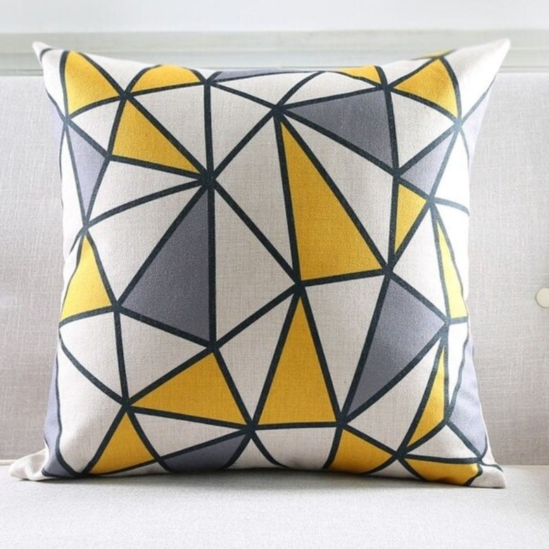 Cushion cover with yellow, grey and white polygons outlined in black.