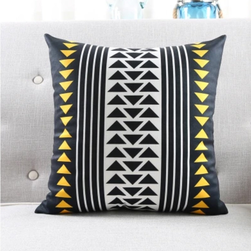 Cushion cover with vertical bands of black, white and yellow triangles and stripes.