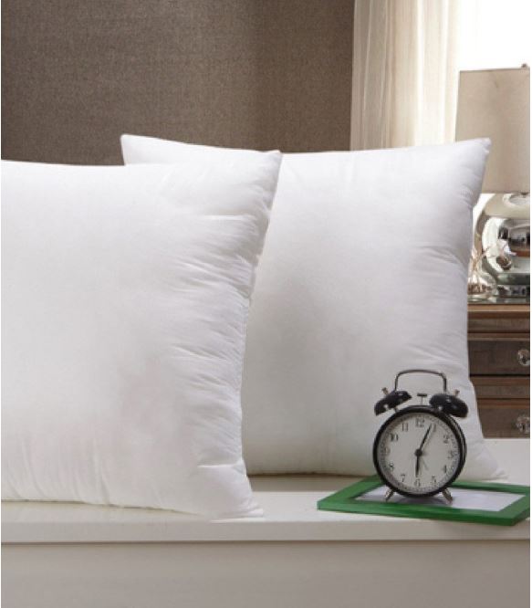 White filled cushions displayed beside a small alarm clock.