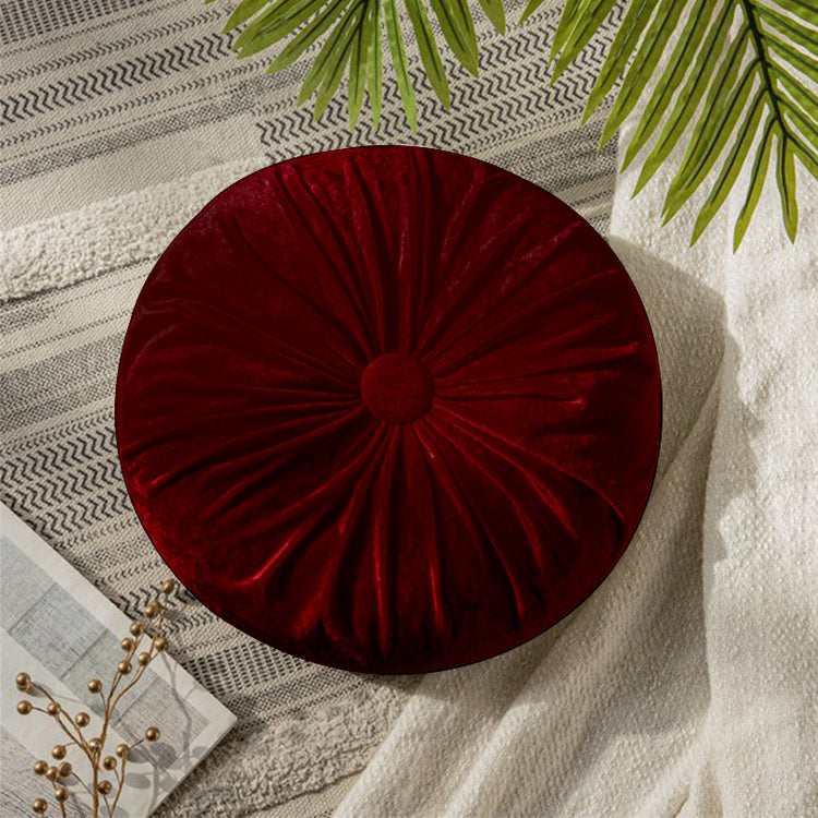 Round dark red cushion with radial pleats and a covered centre button.
