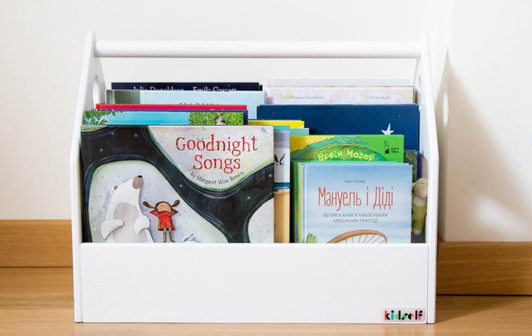 Front view of a white house-shaped book bin with several children's books on display.