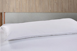 Long white body pillow displayed horizontally on a bed.